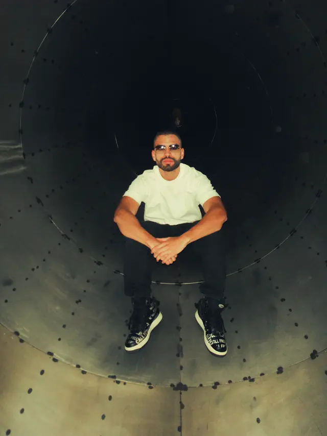 Mexes sentado dentro de un túnel, mirando a la cámara desde abajo
